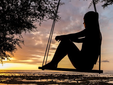 pexels-photo-289998-289998 A serene sunset silhouette of a woman sitting on a swing by the seashore, evoking tranquility and reflection.